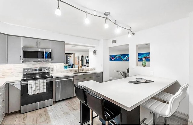 kitchen featuring gray cabinets, appliances with stainless steel finishes, and a breakfast bar