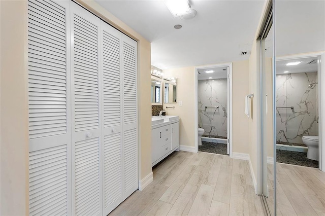 bathroom featuring vanity, hardwood / wood-style floors, walk in shower, and toilet