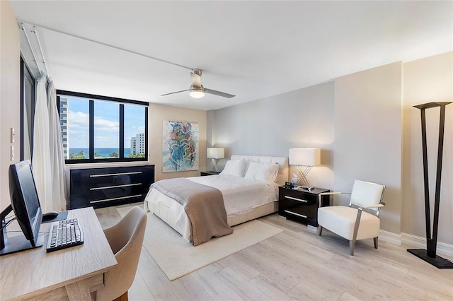 bedroom with light wood-style floors, baseboards, and ceiling fan