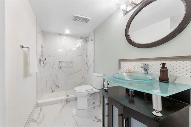 bathroom featuring tasteful backsplash, vanity, tiled shower, and toilet