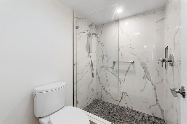 bathroom featuring a marble finish shower and toilet
