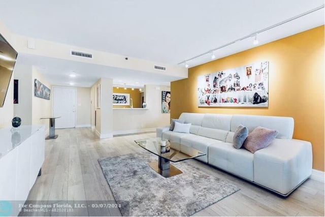 living area featuring baseboards, visible vents, and light wood finished floors