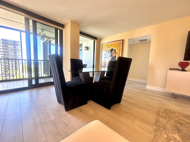 dining space featuring light wood-type flooring, baseboards, visible vents, and floor to ceiling windows