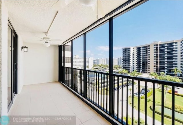 unfurnished sunroom featuring a view of city and ceiling fan