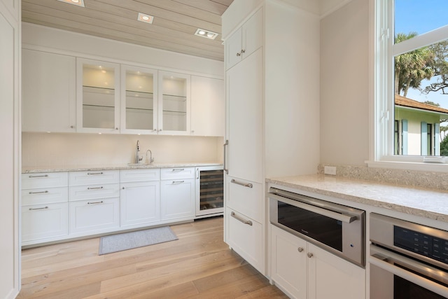 kitchen featuring light stone countertops, white cabinets, appliances with stainless steel finishes, and wine cooler