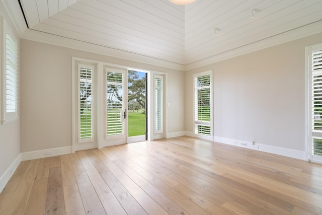 empty room featuring lofted ceiling, crown molding, and light hardwood / wood-style flooring