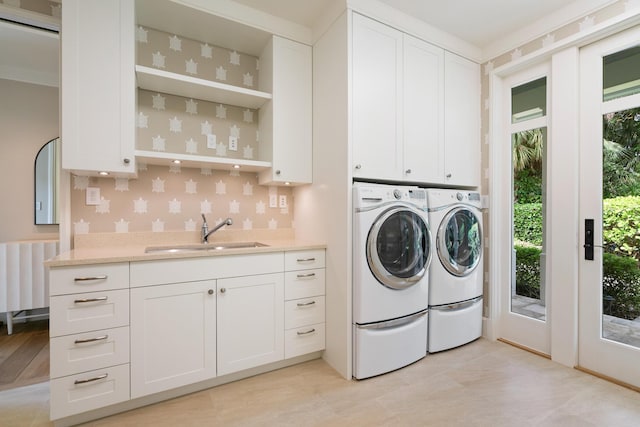 clothes washing area featuring cabinets, sink, and washing machine and dryer