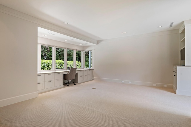 unfurnished office featuring built in desk and light colored carpet