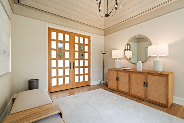 foyer entrance featuring a towering ceiling, a chandelier, light hardwood / wood-style flooring, and french doors