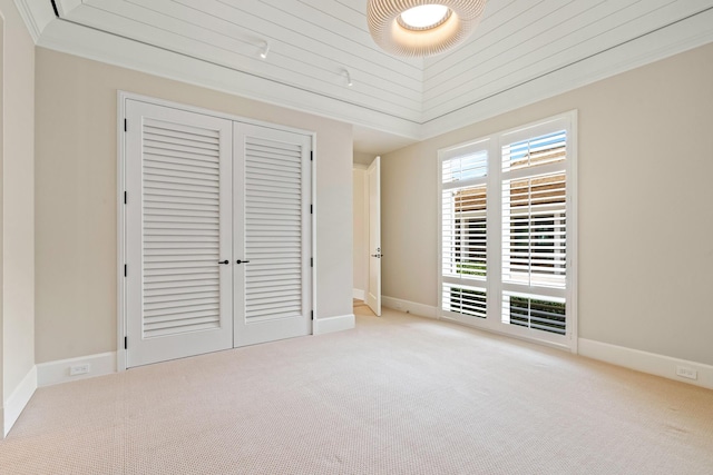 unfurnished bedroom featuring vaulted ceiling, ornamental molding, and light colored carpet