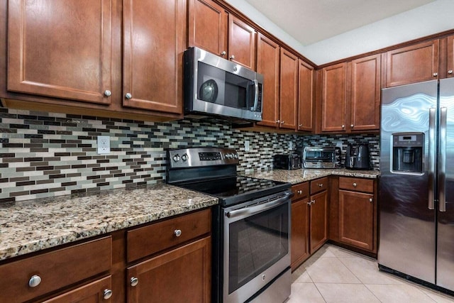 kitchen with decorative backsplash, light stone counters, light tile patterned floors, and stainless steel appliances