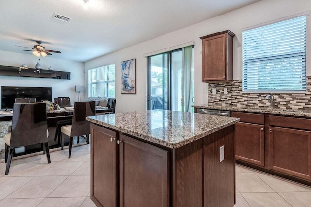 kitchen with a kitchen island, backsplash, light stone counters, and sink