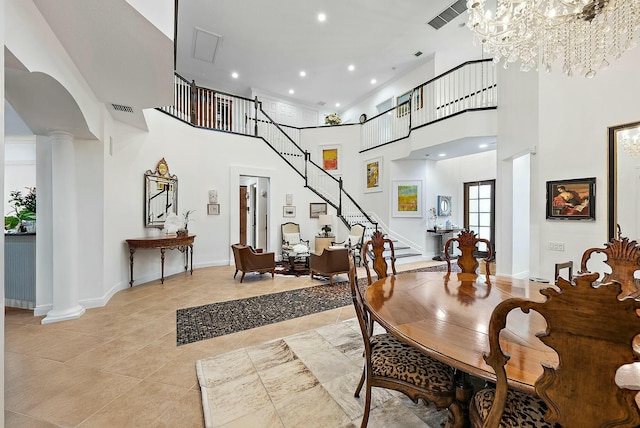 tiled dining space with ornate columns, a chandelier, and a towering ceiling