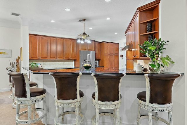 kitchen featuring hanging light fixtures, a breakfast bar, kitchen peninsula, and crown molding