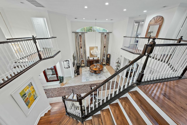 stairway featuring ornamental molding, a towering ceiling, and hardwood / wood-style floors