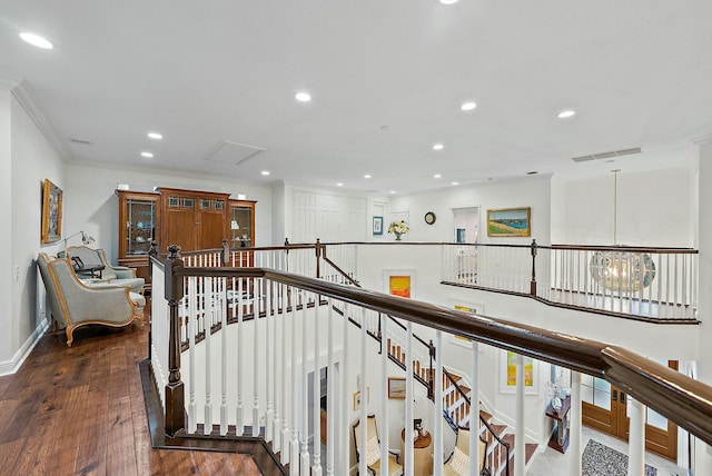 corridor featuring dark wood-type flooring, crown molding, and a notable chandelier