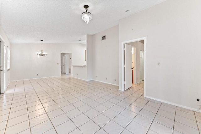 tiled empty room with lofted ceiling, a chandelier, and a textured ceiling