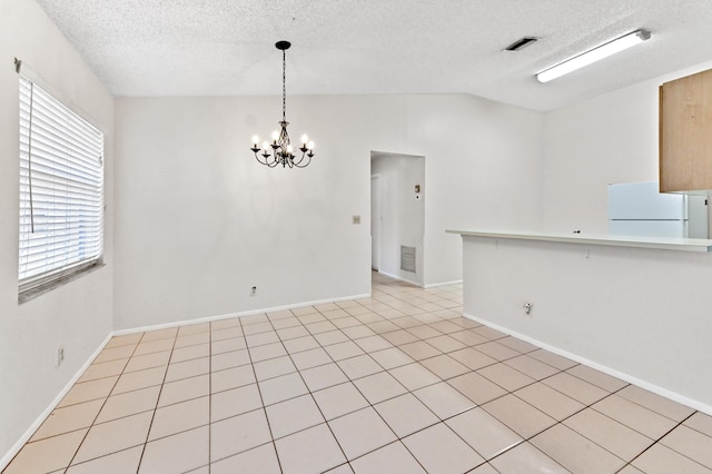 empty room featuring vaulted ceiling, a textured ceiling, and an inviting chandelier