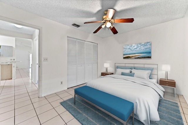 tiled bedroom featuring ceiling fan, a textured ceiling, and a closet