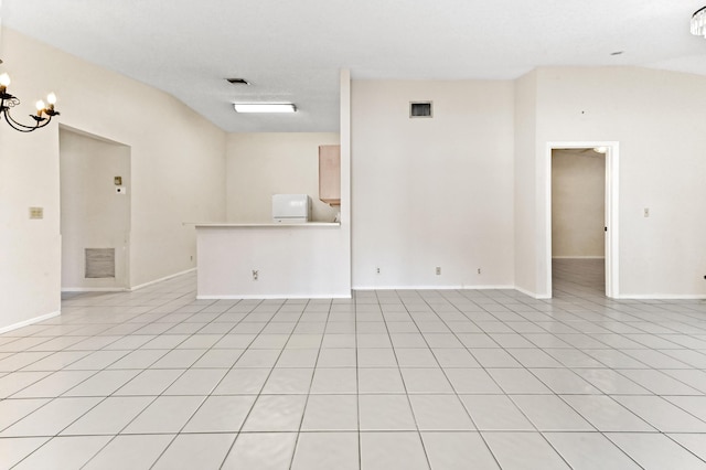 spare room featuring lofted ceiling, light tile patterned floors, and a notable chandelier