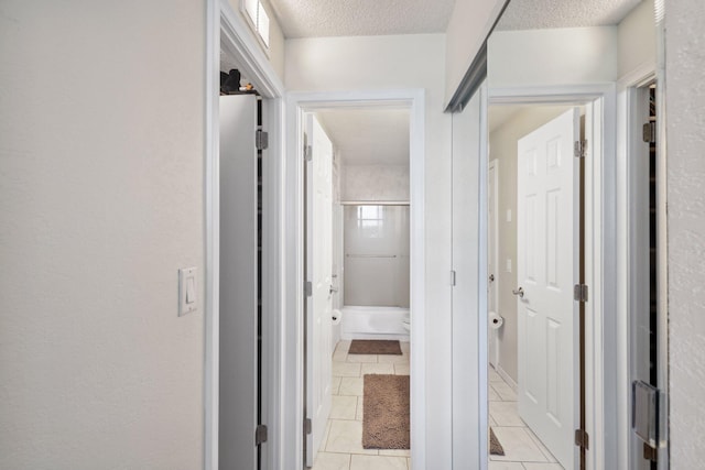 corridor with a textured ceiling and light tile patterned floors