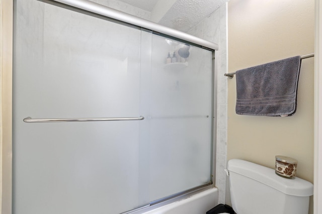 bathroom featuring toilet and bath / shower combo with glass door