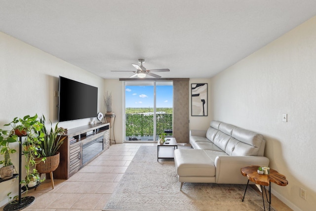 living room featuring ceiling fan, expansive windows, light tile patterned flooring, and a textured ceiling