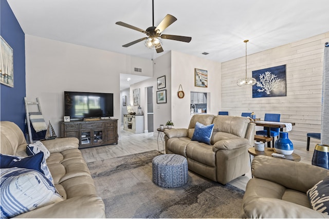 living room with ceiling fan with notable chandelier and hardwood / wood-style flooring