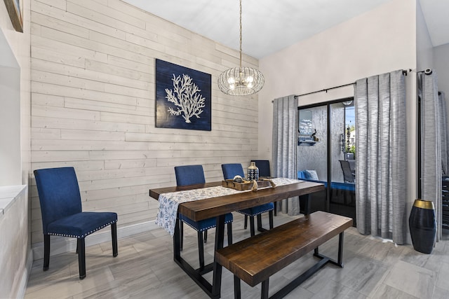 dining room with an inviting chandelier and wood walls