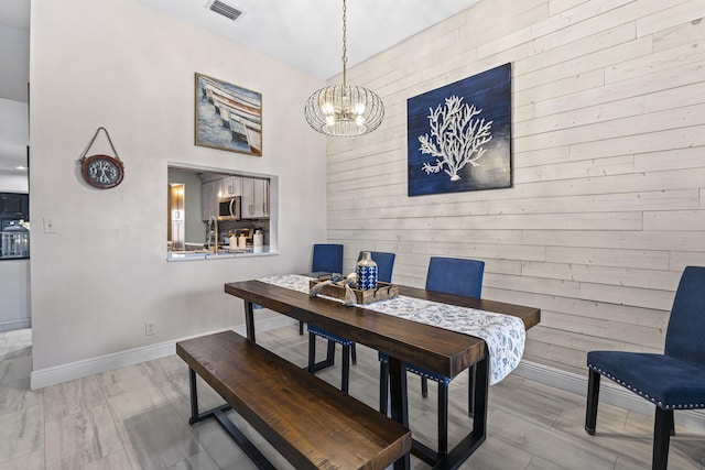 dining room with a chandelier and wooden walls