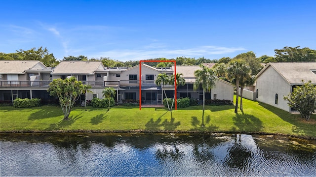 back of property featuring a balcony, a water view, and a lawn