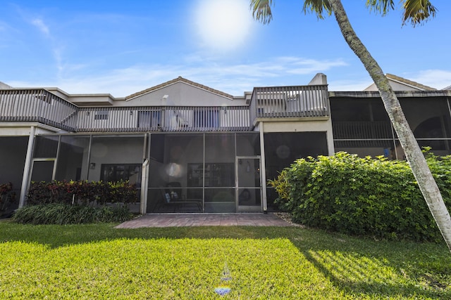 rear view of house featuring a lawn and a balcony