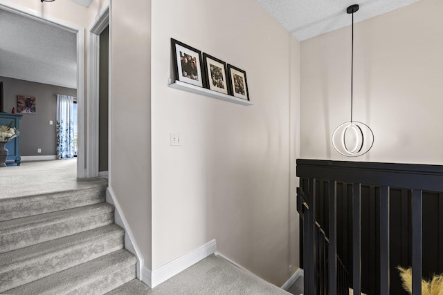 stairway featuring a textured ceiling and carpet flooring