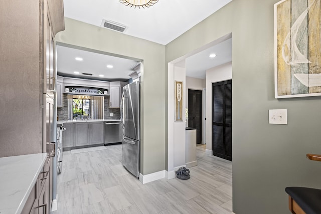 kitchen with decorative backsplash, gray cabinetry, and stainless steel appliances