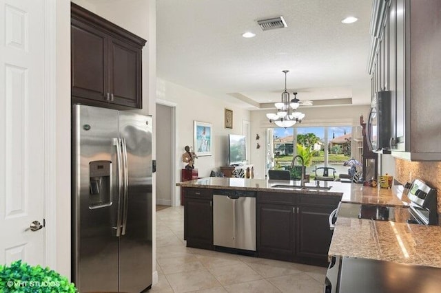 kitchen featuring appliances with stainless steel finishes, sink, a raised ceiling, a chandelier, and dark brown cabinets