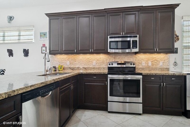 kitchen with dark brown cabinetry, stainless steel appliances, sink, backsplash, and light tile patterned flooring