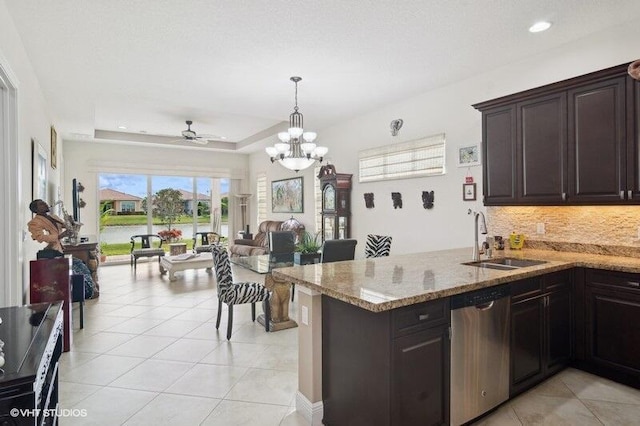 kitchen featuring ceiling fan with notable chandelier, dark brown cabinetry, dishwasher, sink, and a tray ceiling