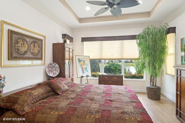 bedroom featuring ceiling fan, light hardwood / wood-style floors, and a raised ceiling