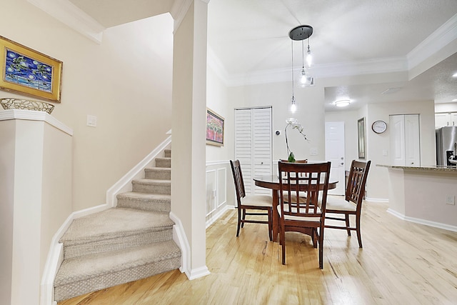 dining space featuring crown molding and light hardwood / wood-style floors