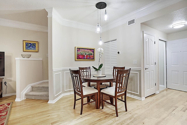 dining room featuring crown molding, a textured ceiling, and light wood-type flooring