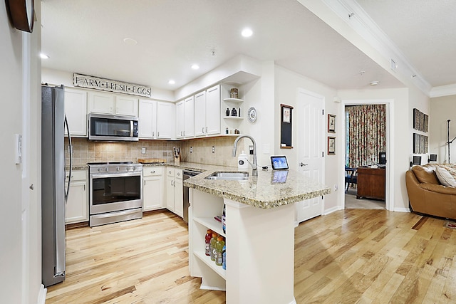 kitchen with sink, white cabinetry, appliances with stainless steel finishes, kitchen peninsula, and light stone countertops