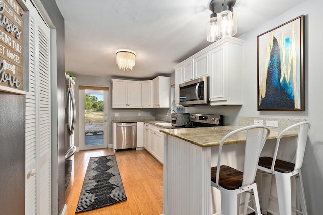 kitchen featuring a breakfast bar area, kitchen peninsula, appliances with stainless steel finishes, and white cabinetry