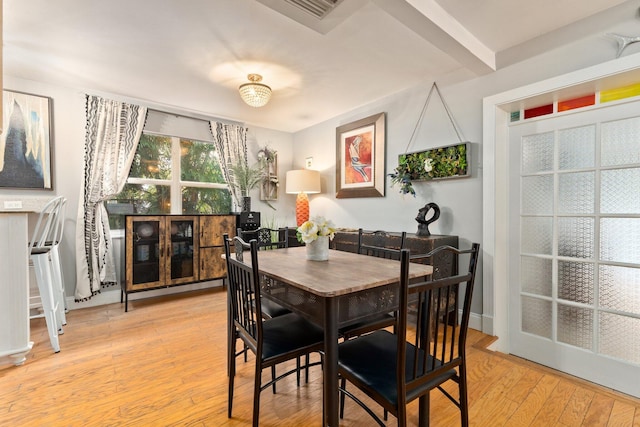 dining space featuring beam ceiling and light wood-type flooring