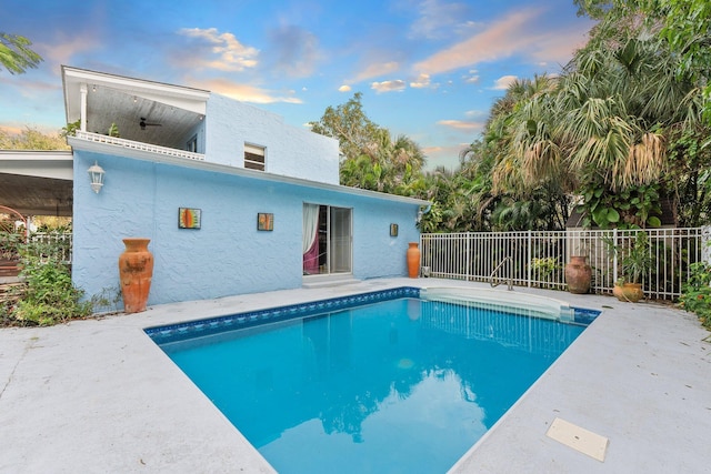 pool at dusk featuring ceiling fan