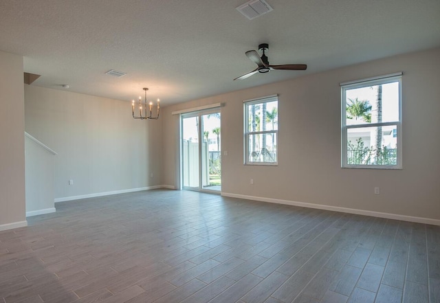 empty room featuring ceiling fan with notable chandelier and a textured ceiling