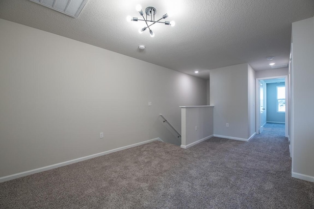 carpeted empty room with a textured ceiling and an inviting chandelier