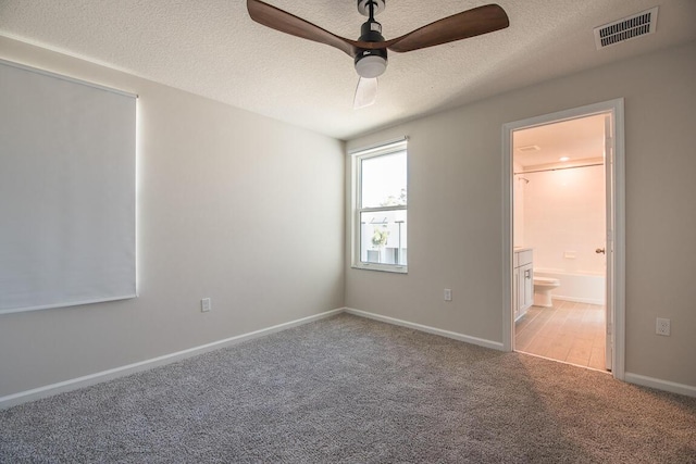 unfurnished bedroom featuring ceiling fan, connected bathroom, carpet floors, and a textured ceiling