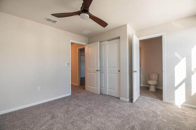 unfurnished bedroom with connected bathroom, ceiling fan, a closet, and light colored carpet