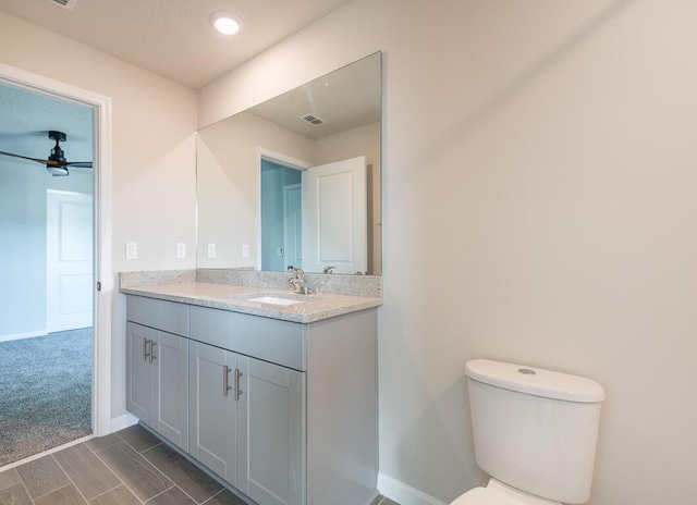 bathroom with toilet, vanity, and ceiling fan