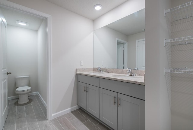 bathroom featuring toilet, a textured ceiling, and vanity